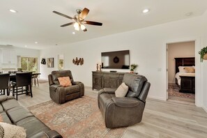 A spacious living room with leather sofas, a large rug, a ceiling fan, and a flat-screen TV on a wooden cabinet. - NEW LISTING SALE: Peaceful 2BD/2.5BA Townhome w/ Forest Setting, Patio, & Garage (Payson)