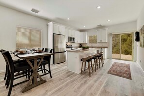 A modern kitchen with white cabinets, stainless steel appliances, and a central island with bar stools. - NEW LISTING SALE: Peaceful 2BD/2.5BA Townhome w/ Forest Setting, Patio, & Garage (Payson)