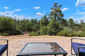An outdoor seating area with a table and chairs, surrounded by a forested landscape. - NEW LISTING SALE: Peaceful 2BD/2.5BA Townhome w/ Forest Setting, Patio, & Garage (Payson)