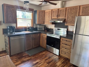 A kitchen with wooden cabinets, stainless steel appliances, a window, and a ceiling fan. - Large Backyard, River Views & Mountain Adventures (Gunnison)