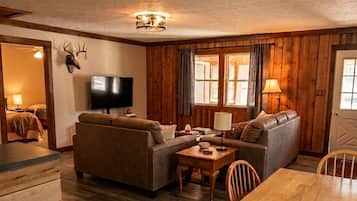 Una sala de estar acogedora con sofá, televisor y paredes de madera.