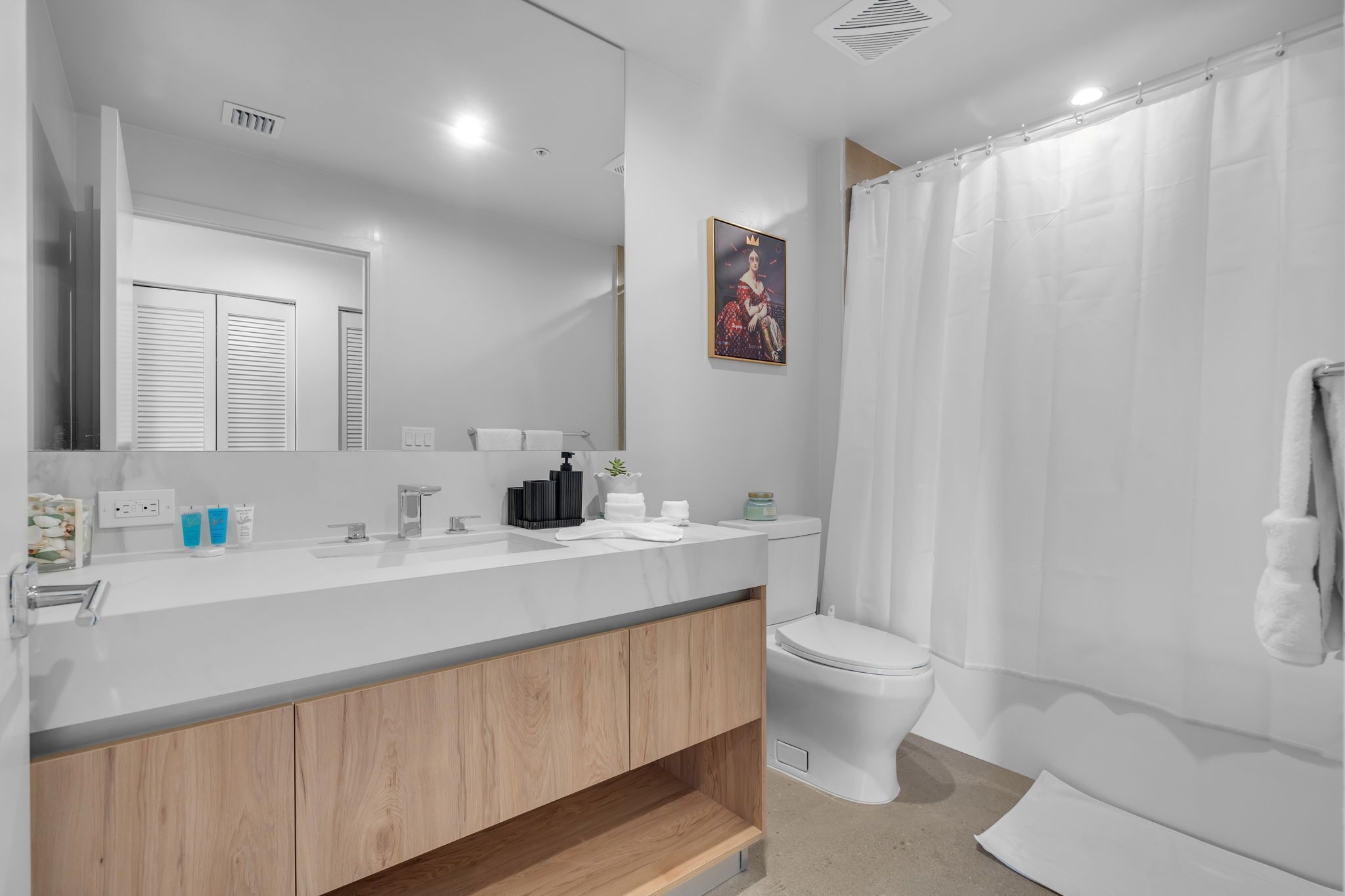 A modern bathroom with a white vanity, a toilet, and a shower curtain.