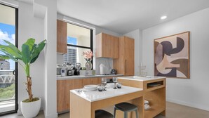 A modern kitchen with a central island, wooden cabinets, and a large window. - The Crosby Miami Worldcenter (Miami)