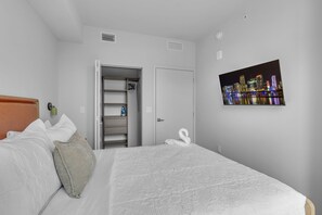 A hotel room with a bed, a wardrobe, a mirror, a picture of a cityscape, and a door. - The Crosby Miami Worldcenter (Miami)