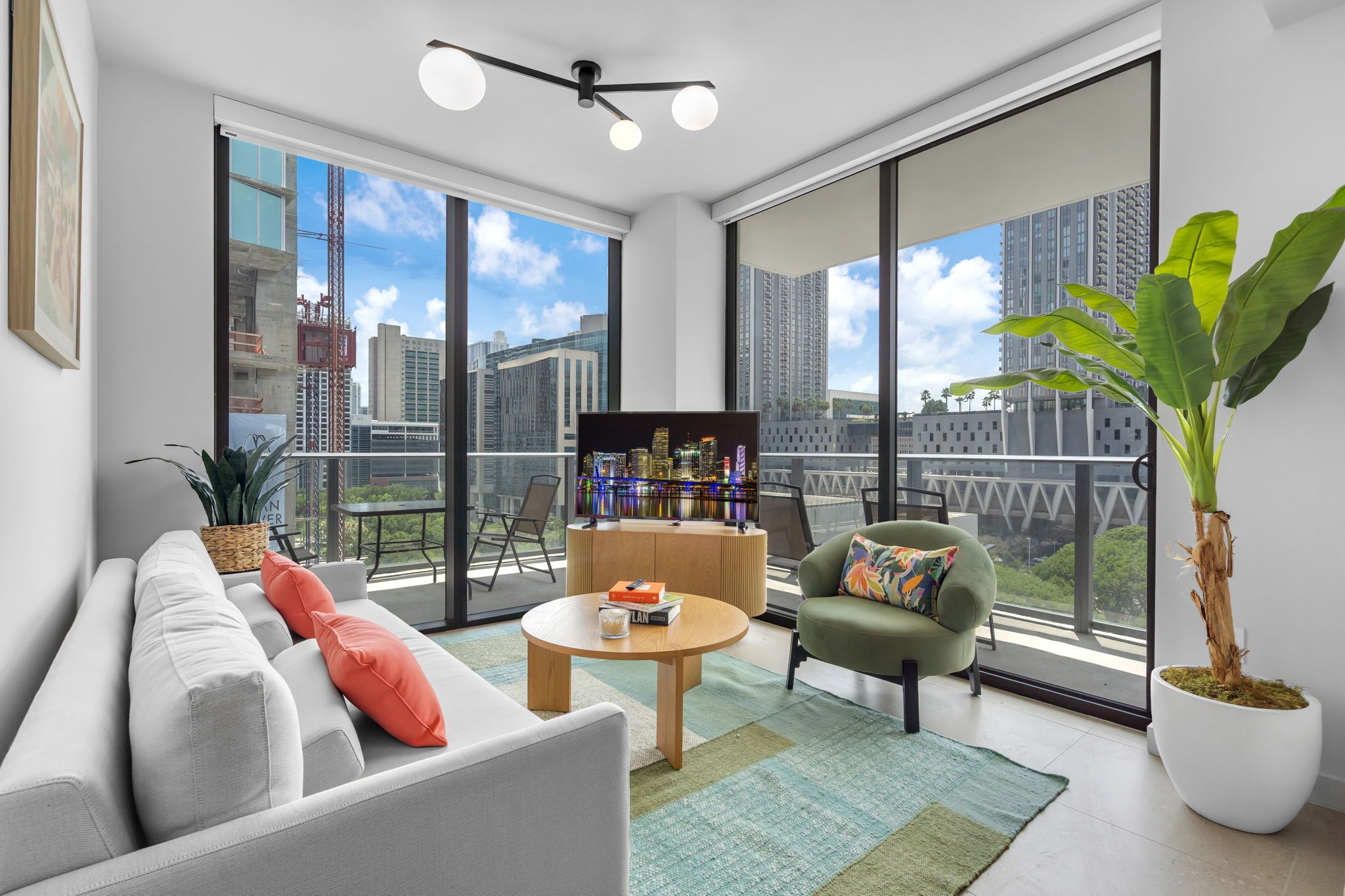 A modern living room with a sofa, armchairs, a coffee table, and a large potted plant.
