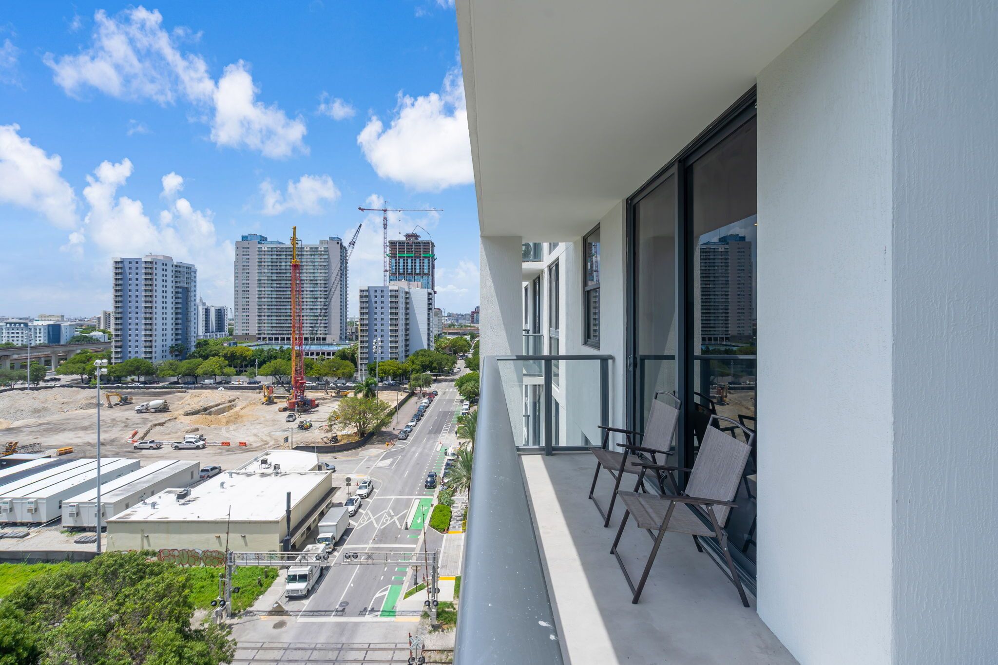 A balcony with a view of a cityscape, including high-rise buildings and construction cranes.