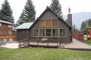 Eine Holzhütte mit einer Veranda, großen Fenstern und einem Schornstein.