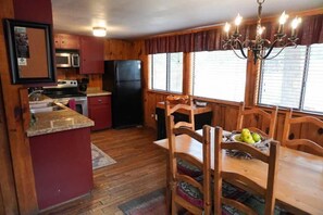 A kitchen with wooden cabinets, a refrigerator, a microwave, and a dining table with chairs.