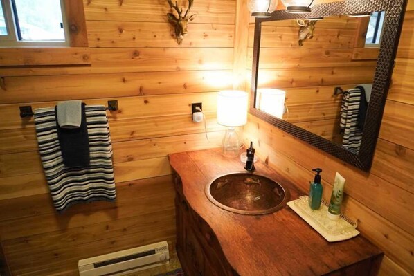 A wooden cabin bathroom with a wooden sink, a mirror, a towel rack, and a window. - Silver Street Retreat - Great Location Close to Historic Lake City (Lake City)