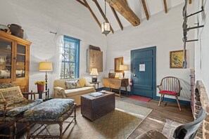 Un salon rustique avec des poutres apparentes, une porte bleue et un mobilier traditionnel.