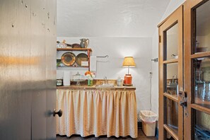 A small kitchen with a wooden counter, a sink, a lamp, and various kitchen items. - An 1849 farmhouse that traveled 1,200 miles (Fredericksburg)