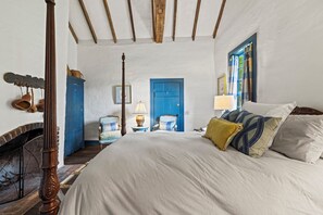 A bedroom with a four-poster bed, a blue door, and a window with curtains. - An 1849 farmhouse that traveled 1,200 miles (Fredericksburg)