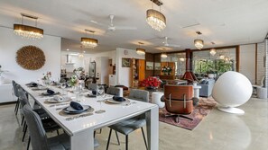 Un comedor moderno con una mesa larga dispuesta para una comida, una zona de estar con sofás y una gran esfera decorativa.