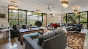 Um quarto amplo com área de jantar, janelas grandes e mobiliário moderno.
