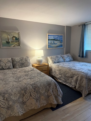 A hotel room with two beds, a nightstand with a lamp, and two paintings on the wall. - Oceanfront Paradise in Madeira Beach. Private Balcony. Pool & Hot Tub (Madeira Beach)