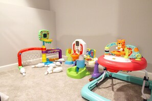A play area with various toys and equipment, including a bowling set, a toy car, and a toy train.