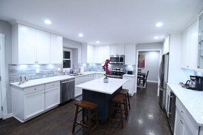 A modern kitchen with white cabinetry, a central island, and stainless steel appliances.