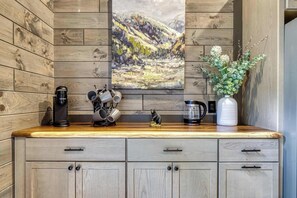 Eine Küchenarbeitsplatte mit Kaffeemaschine, Wasserkocher und einer Vase mit Blumen.