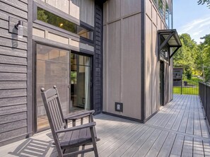 A modern building with a wooden deck, a glass door entrance, and a bench. - Bear Trap in the Glades (Gatlinburg)