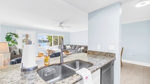 Eine moderne Küche mit einer Granit-Arbeitsplatte, einer eingebauten Spüle und einem Deckenventilator.