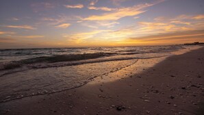 Ein Strand mit Wellen und einem Sonnenuntergang.