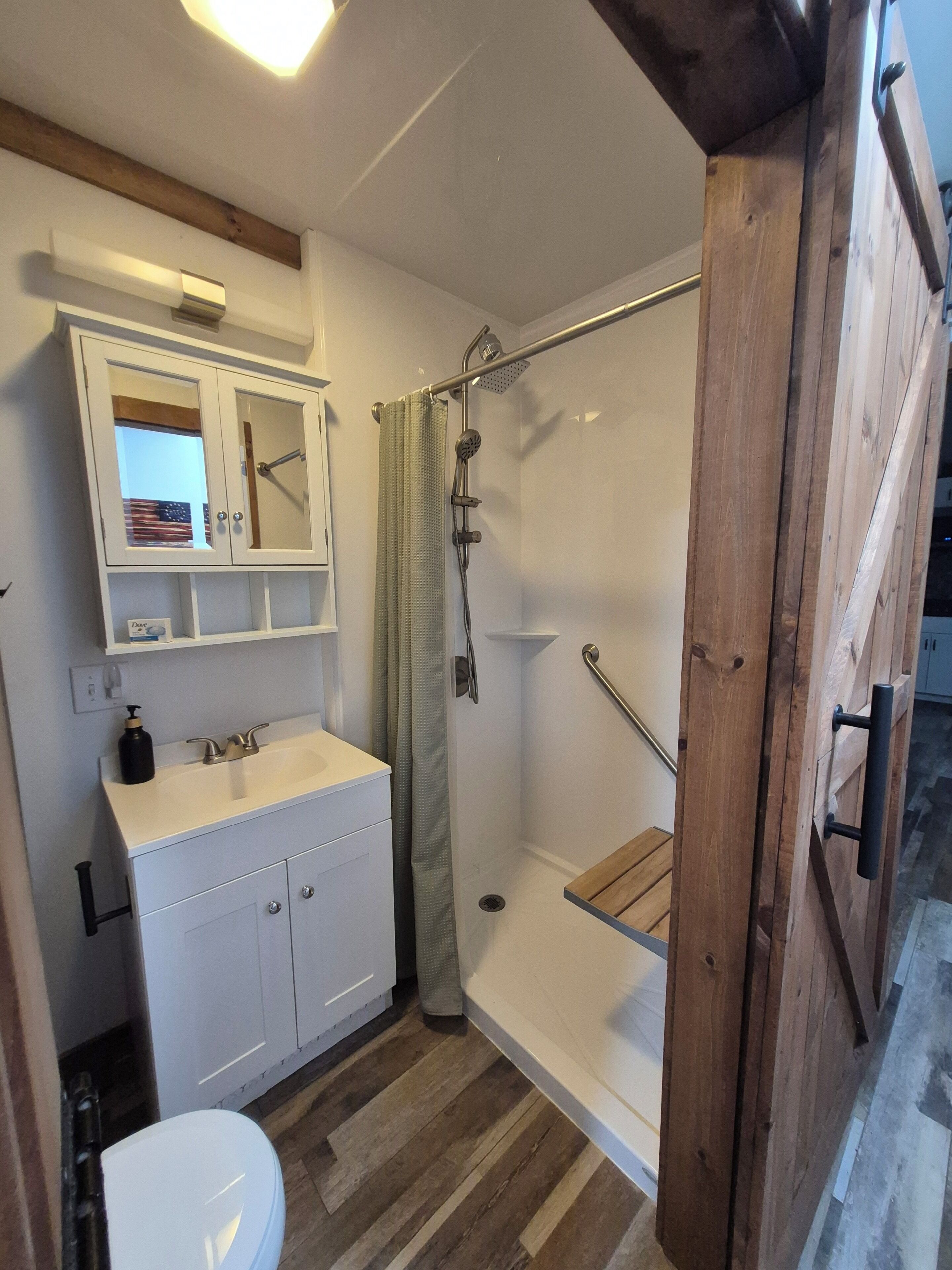Une salle de bain équipée d’une douche, de toilettes, d’un lavabo et d’un miroir au-dessus du lavabo.