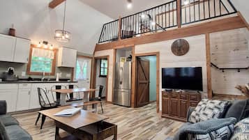A spacious living area with a dining table, sofas, and a TV.