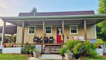 A two-story house with a porch, a red door, and potted plants.