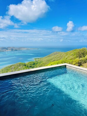 Ein Pool mit Blick auf den Ozean und die Hügel.
