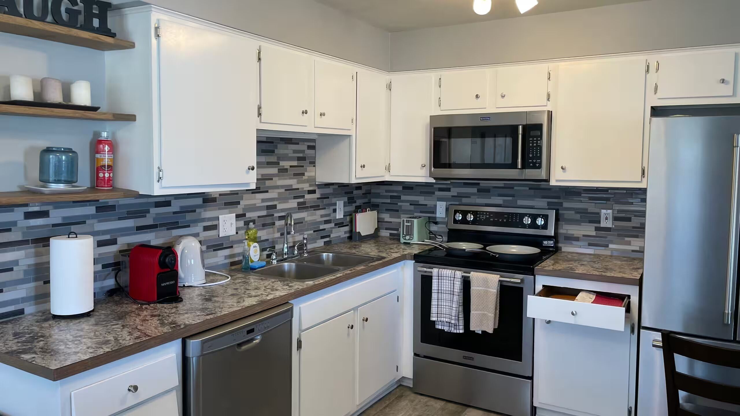 A modern kitchen with white cabinets, a stainless steel microwave, a built-in oven, and a dishwasher.