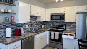 A modern kitchen with white cabinets, a stainless steel microwave, a built-in oven, and a dishwasher.