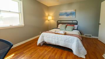 Un dormitorio con una cama, un ventilador de techo, una ventana y un cuadro en la pared.