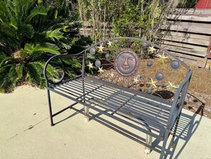 Un banco de metal con un respaldo decorativo que presenta un diseño circular y elementos en forma de estrella.