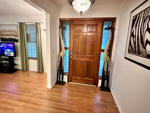 Un pasillo con una puerta de madera, un televisor y un cuadro en la pared.