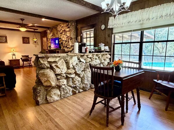 Un interior rústico con una barra de piedra, una mesa de comedor de madera y sillas.