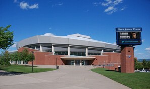 A large, modern sports stadium with a prominent entrance and a digital display board.