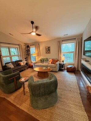 A living room with a ceiling fan, two sofas, a coffee table, and a television. - Dog-Friendly Mountain Home w/ Hot Tub & Rec Room (Asheville)