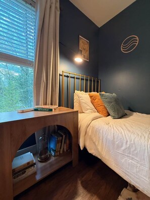 A bedroom with a bed, a nightstand, a window with curtains, and a wall with a circular design. - Dog-Friendly Mountain Home w/ Hot Tub & Rec Room (Asheville)