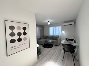 A modern living room with a grey sofa, a small round table, a desk with a chair, and a framed artwork on the wall. - New Charming & Stylish 3-bedroom house with AC in lively Shibuya, 4min Shinjuku (Shibuya)