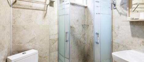 A bathroom with a glass-enclosed shower, a toilet, and a sink.