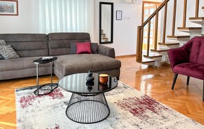 A living room with a grey sofa, a round coffee table, a red chair, and a staircase. - Amazing home in Novi Marof - Kljuc with sauna (Novi Marof - Kljuc)