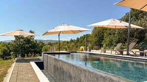 A pool area with lounge chairs and umbrellas. - Amazing home in Novi Marof - Kljuc with sauna (Novi Marof - Kljuc)