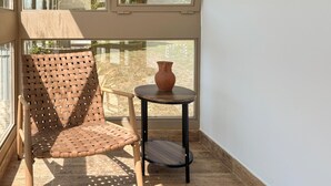 A wicker chair and a small table with a vase on a balcony with a view of greenery. - Amazing home in Novi Marof - Kljuc with sauna (Novi Marof - Kljuc)