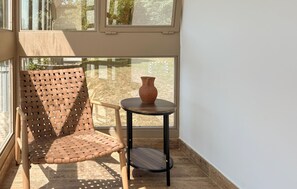 A wicker chair and a small table with a vase on a balcony with a view of greenery. - Amazing home in Novi Marof - Kljuc with sauna (Novi Marof - Kljuc)