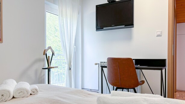 A hotel room with a bed, a desk, a chair, a TV, and a window with curtains. - Amazing home in Novi Marof - Kljuc with sauna (Novi Marof - Kljuc)
