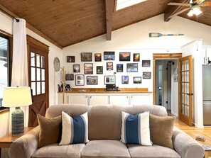 Ein gemütliches Wohnzimmer mit einer Couch, einer Holzbalkendecke und einer Bildergalerie an der Wand.