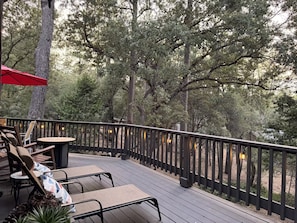 Eine Terrasse im Freien mit Holzbalkon, Sitzgelegenheit und Lichterketten.