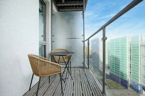 A balcony with two wicker chairs and a small round table, overlooking a cityscape with modern buildings. - Stylish Flat • City Centre • Balcony • FreeParking (Milton Keynes)