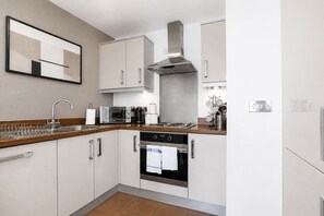 A modern kitchen with white cabinets, stainless steel appliances, and a wooden countertop. - Stylish Flat • City Centre • Balcony • FreeParking (Milton Keynes)