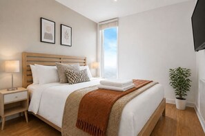 A bedroom with a bed, bedside tables, a window, and a potted plant. - Stylish Flat • City Centre • Balcony • FreeParking (Milton Keynes)